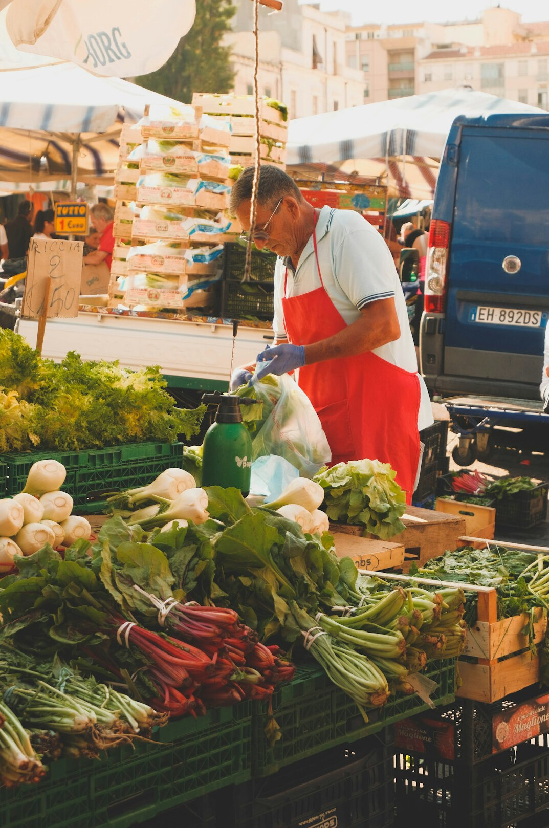 Vendor arranging produce at an outdoor market stall